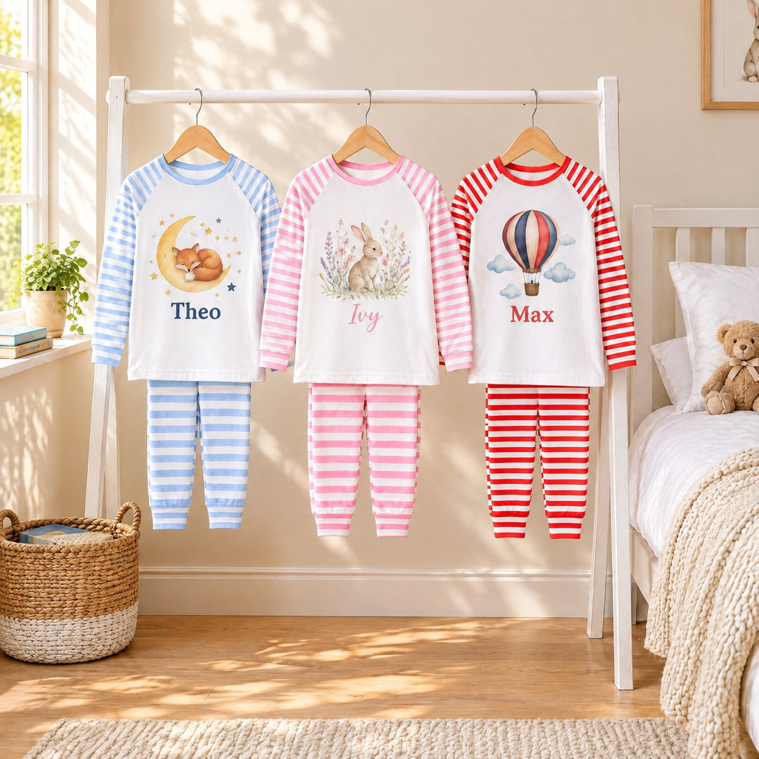 Children’s sublimation pyjamas: three striped sets on a nursery rail, printed with a sleeping fox and the name Theo, a rabbit with Ivy and a hot-air balloon with Max