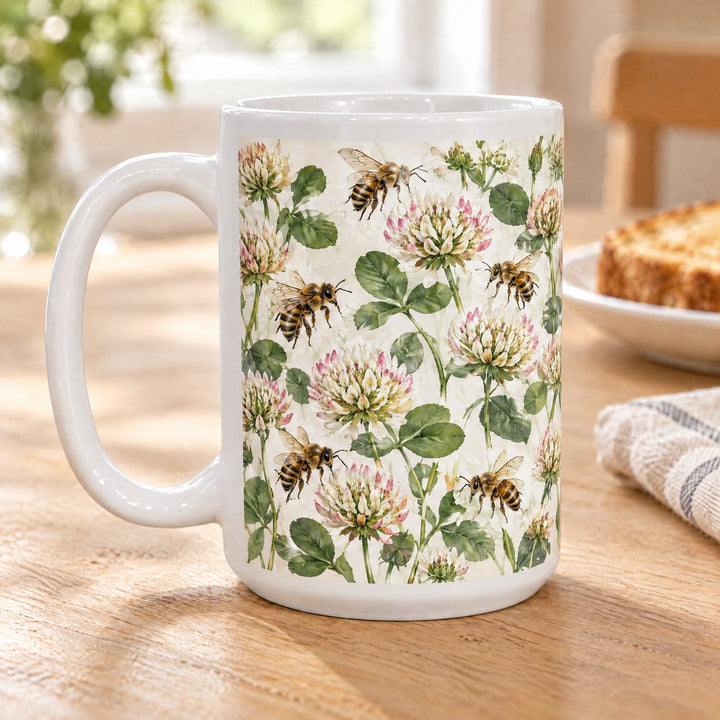 15oz white sublimation mug printed with honeybees and clover flowers, on a wooden breakfast table beside toast