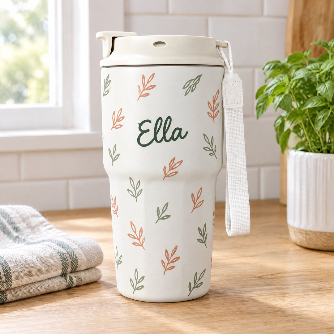 16oz sublimation coffee cup printed with line-drawn leaves and the name Ella, standing on a kitchen worktop