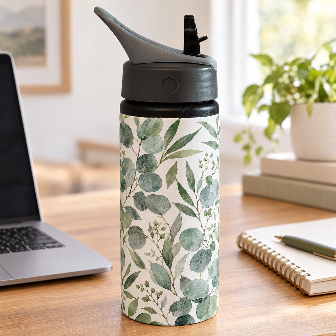 22oz white aluminium bottle 650ml printed with a eucalyptus and sage-green botanical design, on a wooden desk