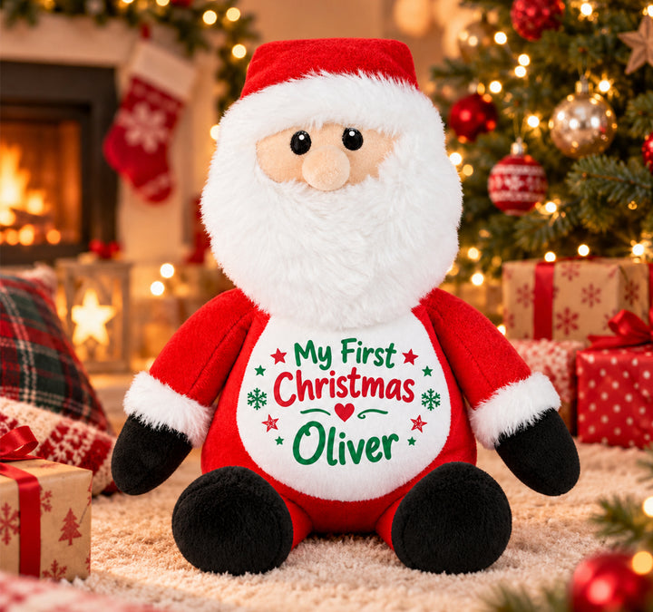 Personalised Santa plush toy with "My First Christmas Oliver" design, sitting by a Christmas tree 