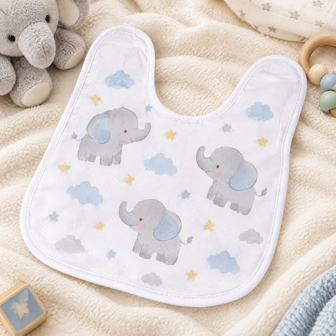 Baby bib, white, printed with little elephants and clouds, laid flat on a blanket