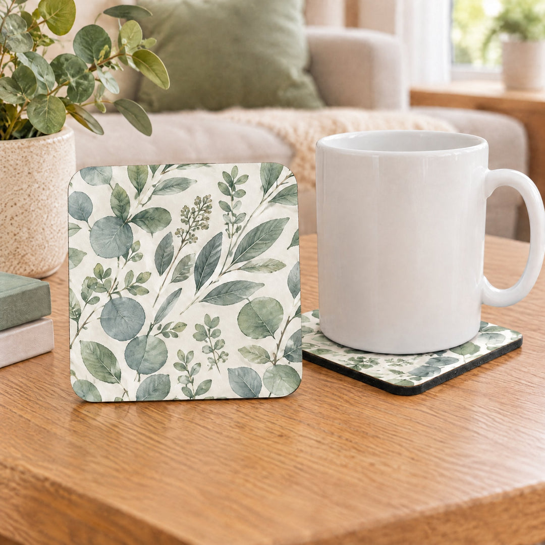 Square MDF coaster with cork printed with a eucalyptus and sage-green botanical design, on a wooden coffee table