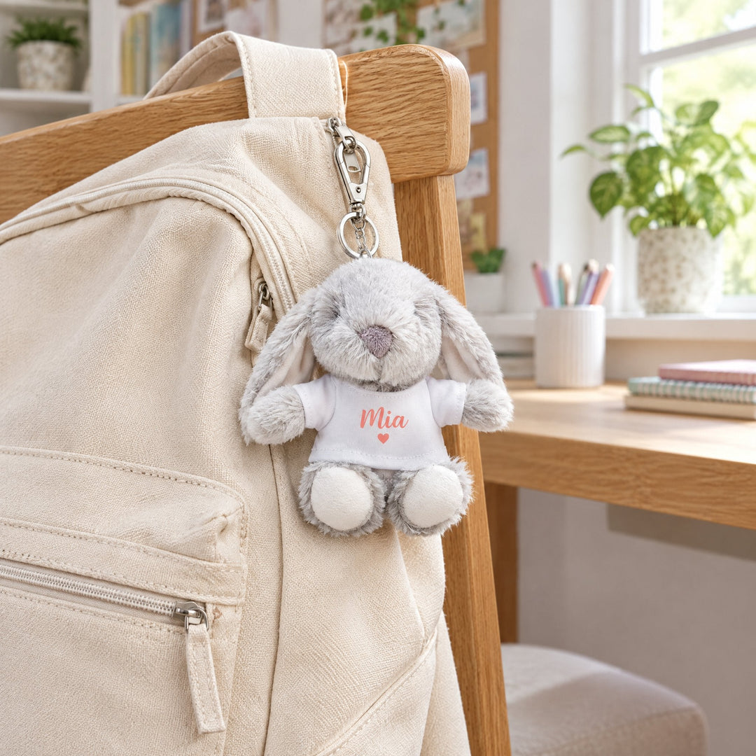 Sublimation T-shirt for the plush keyrings printed with a coral heart design and the name Mia, clipped to a canvas backpack