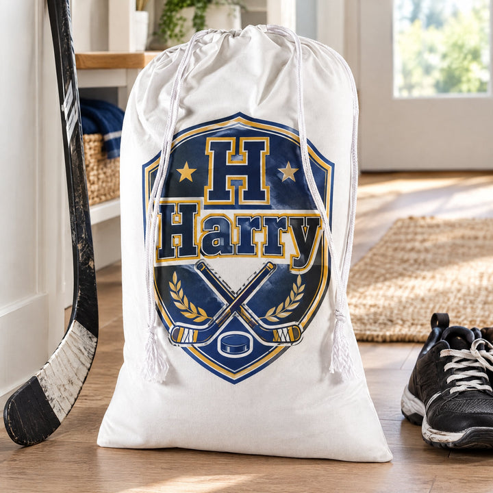 White cotton drawstring sacks 50 x 75cm printed with a hockey crest and the name Harry, by a hockey stick in a hallway