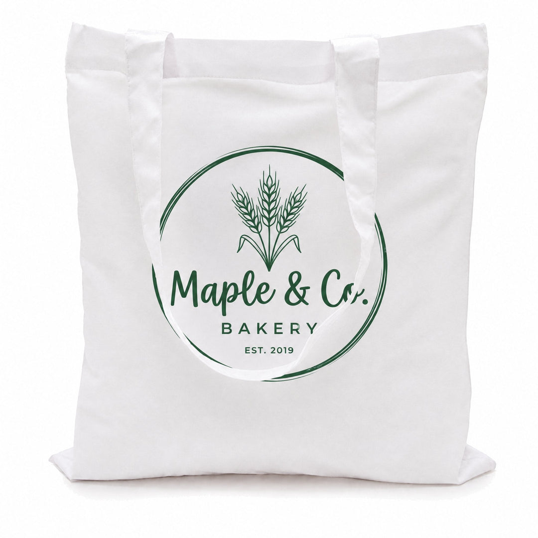 White cotton tote bags printed with a green wheat-sheaf logo reading &