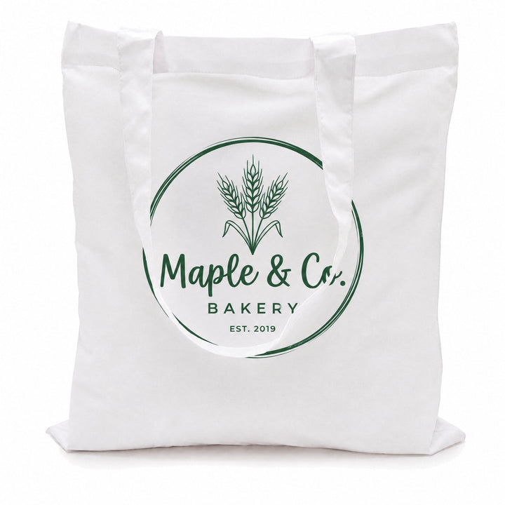 White cotton tote bags printed with a green wheat-sheaf logo reading &